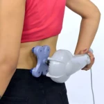 Masajeador eléctrico blanco con cabezal púrpura en uso en la espalda de mujer con top rosa y pantalón negro.