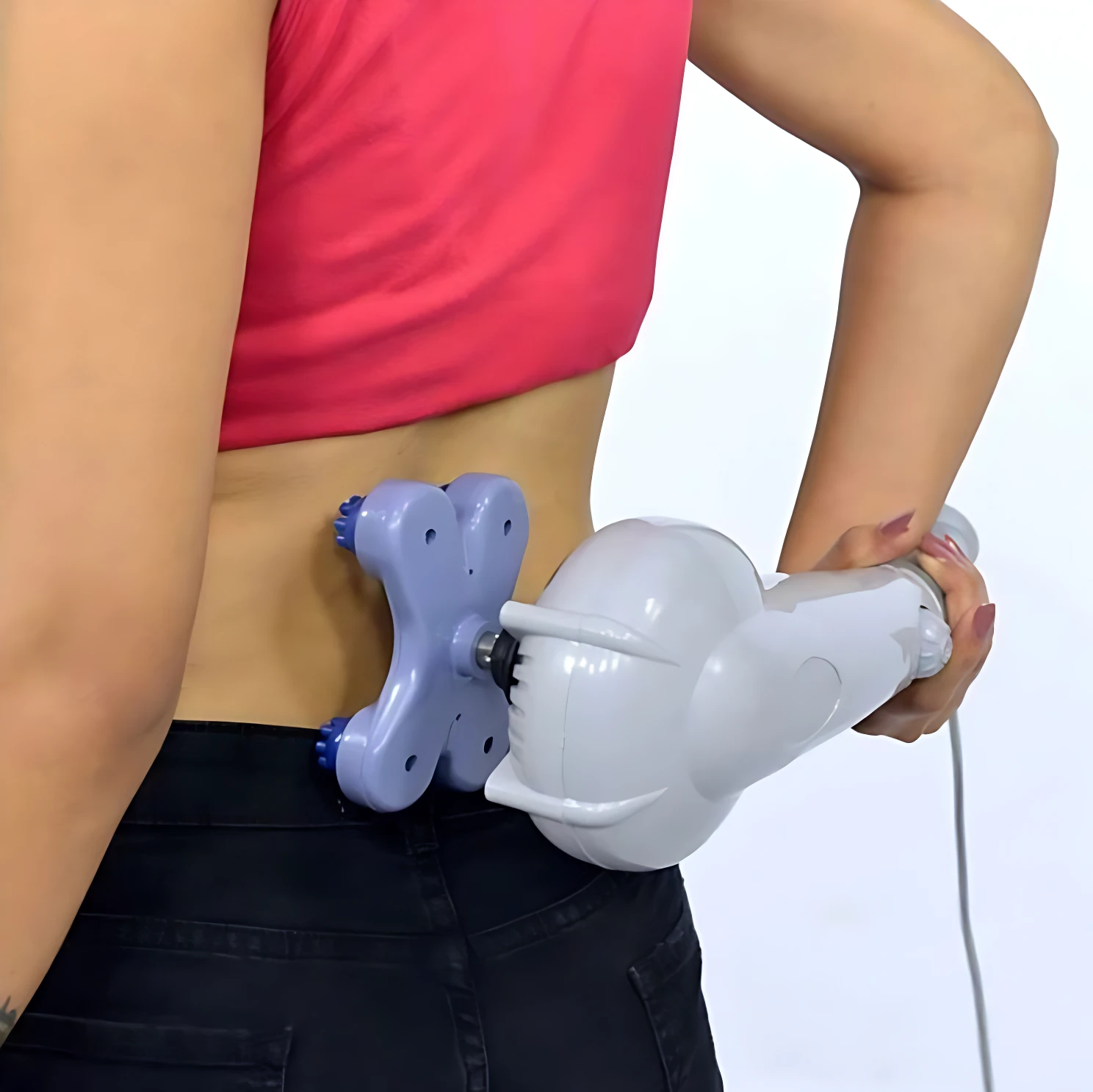 Masajeador eléctrico blanco con cabezal púrpura en uso en la espalda de mujer con top rosa y pantalón negro.