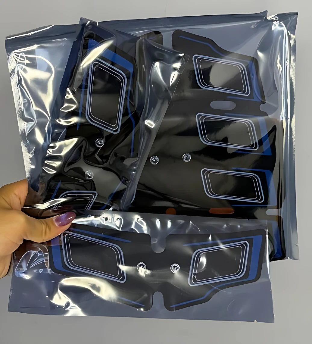 Tres masajeadores escultor EMS en bolsas de plástico transparente, mostrando diseño negro con detalles azules y blancos, visibles desde ángulo superior.