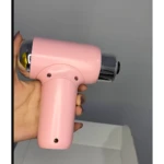 Masajeador percutor portátil en color rosa pastel, con cabezal cromado y mango ergonómico, sostenido en mano para mostrar su tamaño compacto.