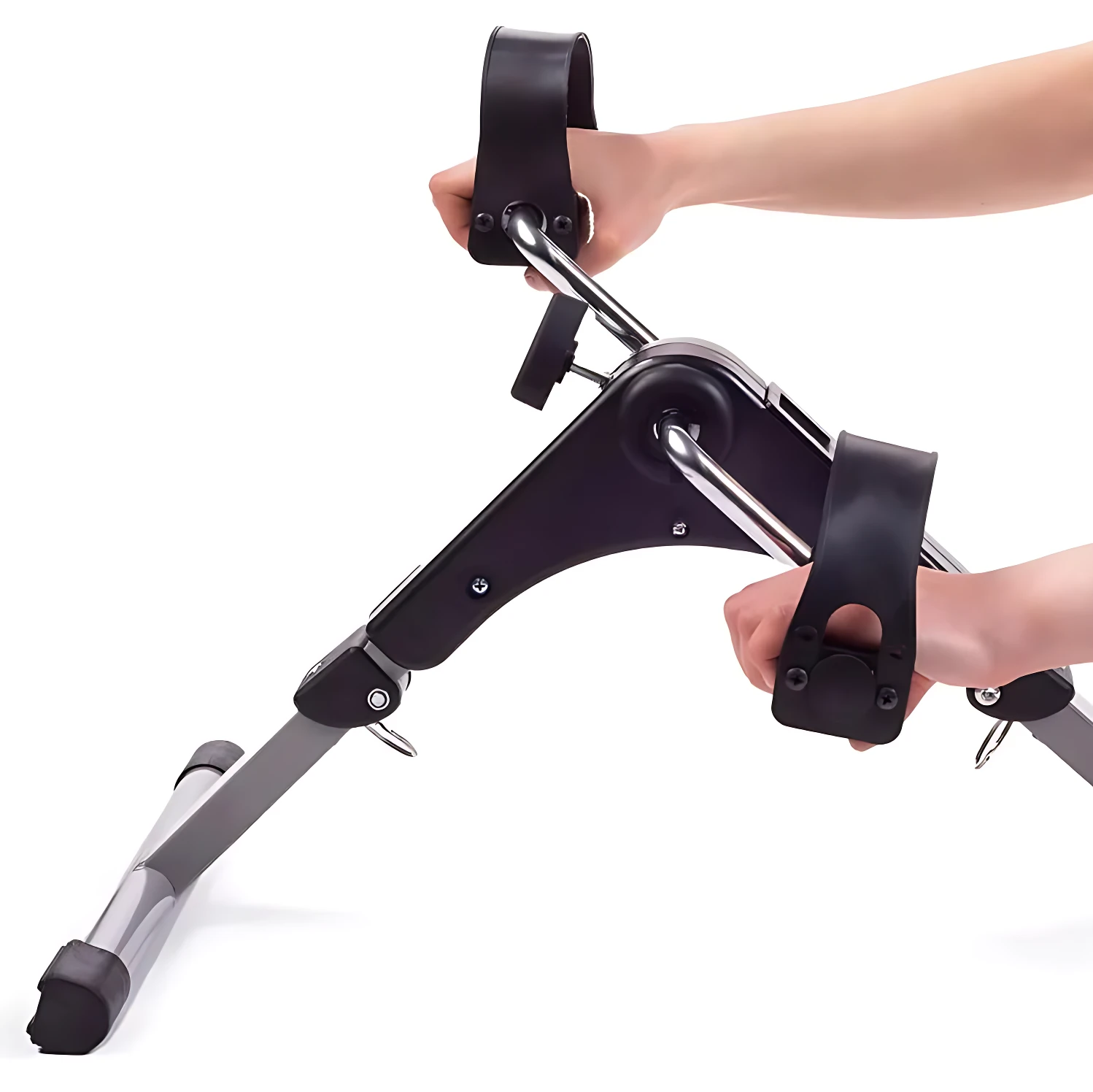 Mini bicicleta spinning compacta en color negro con asideros y correas de seguridad, siendo usada por manos humanas sobre fondo blanco.