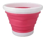 Lavadora portátil compacta en color rosa con base blanca, diseño plegable para uso doméstico.