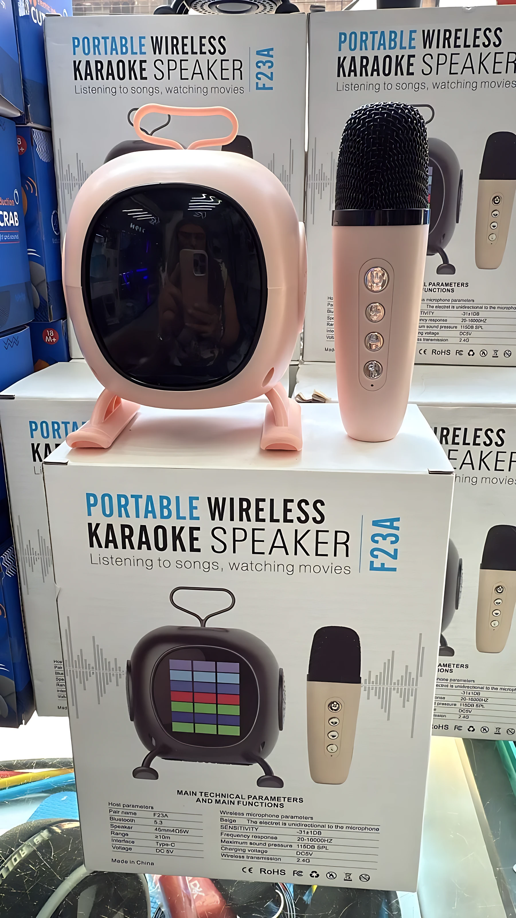 Mini parlante karaoke inalámbrico color rosa con micrófono incluido, sobre su caja de presentación.