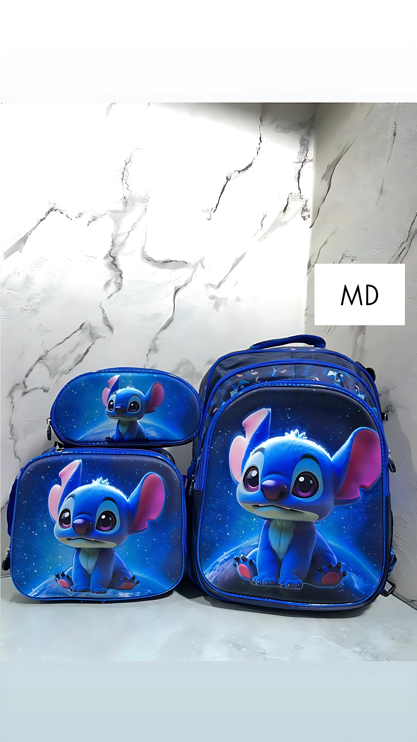Set de tres mochilas escolares con Stitch en relieve azul, incluyendo mochila grande, lonchera térmica y estuche para lápices, sobre fondo de mármol blanco.