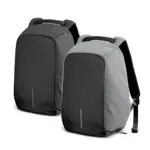 Dos morrales impermeables antirrobo; uno completamente negro y otro gris con frente negro, ambos con diseño minimalista, asa superior y puerto USB visible.