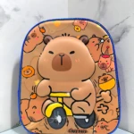 Mochila escolar infantil compacta con cierre único, diseño de capibara montando triciclo amarillo sobre fondo beige con estampado repetido.