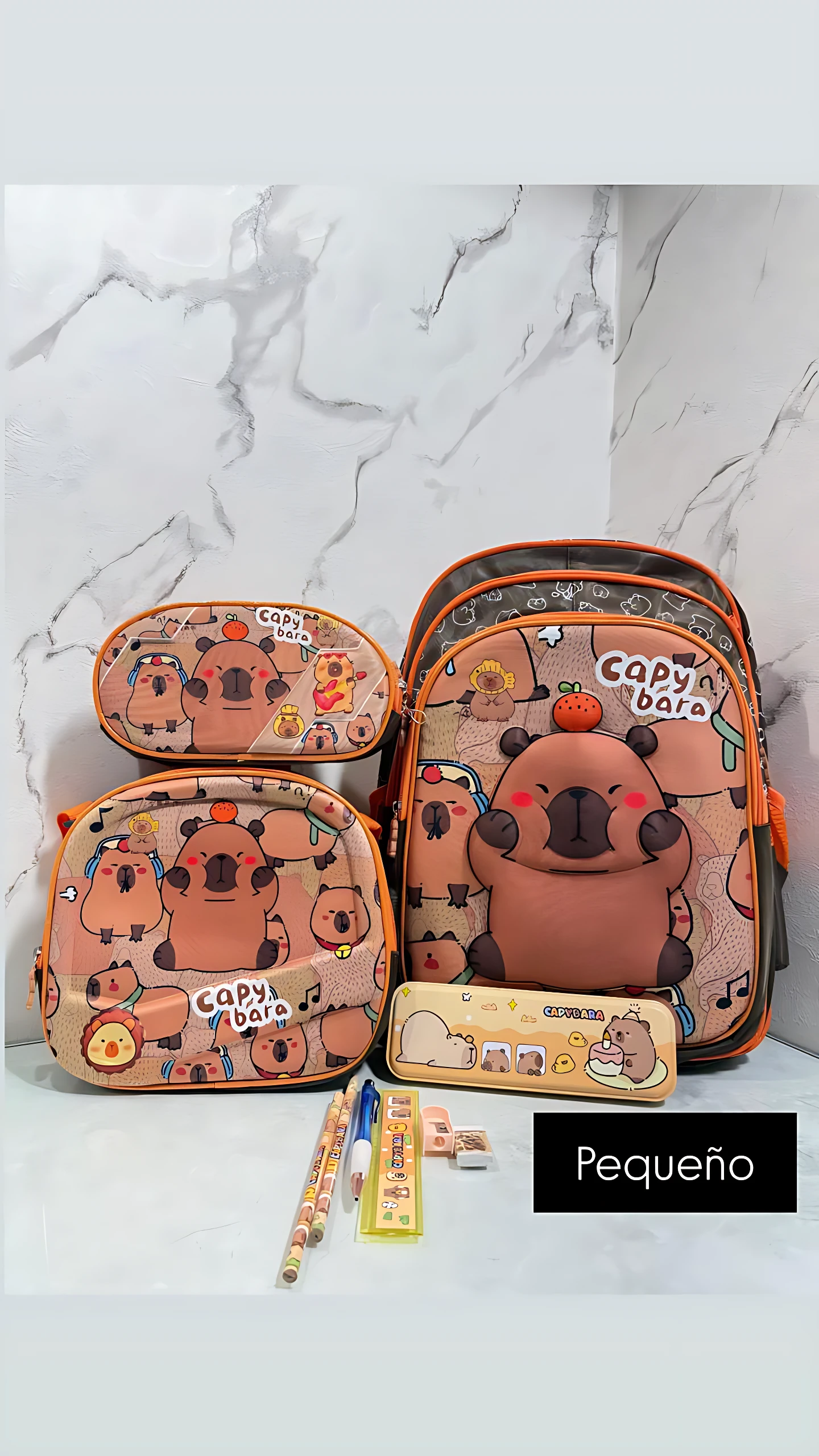 Mochila escolar pequeña con lonchera integrada, diseño de capibara en tonos tierra, incluye estuche y accesorios visibles.