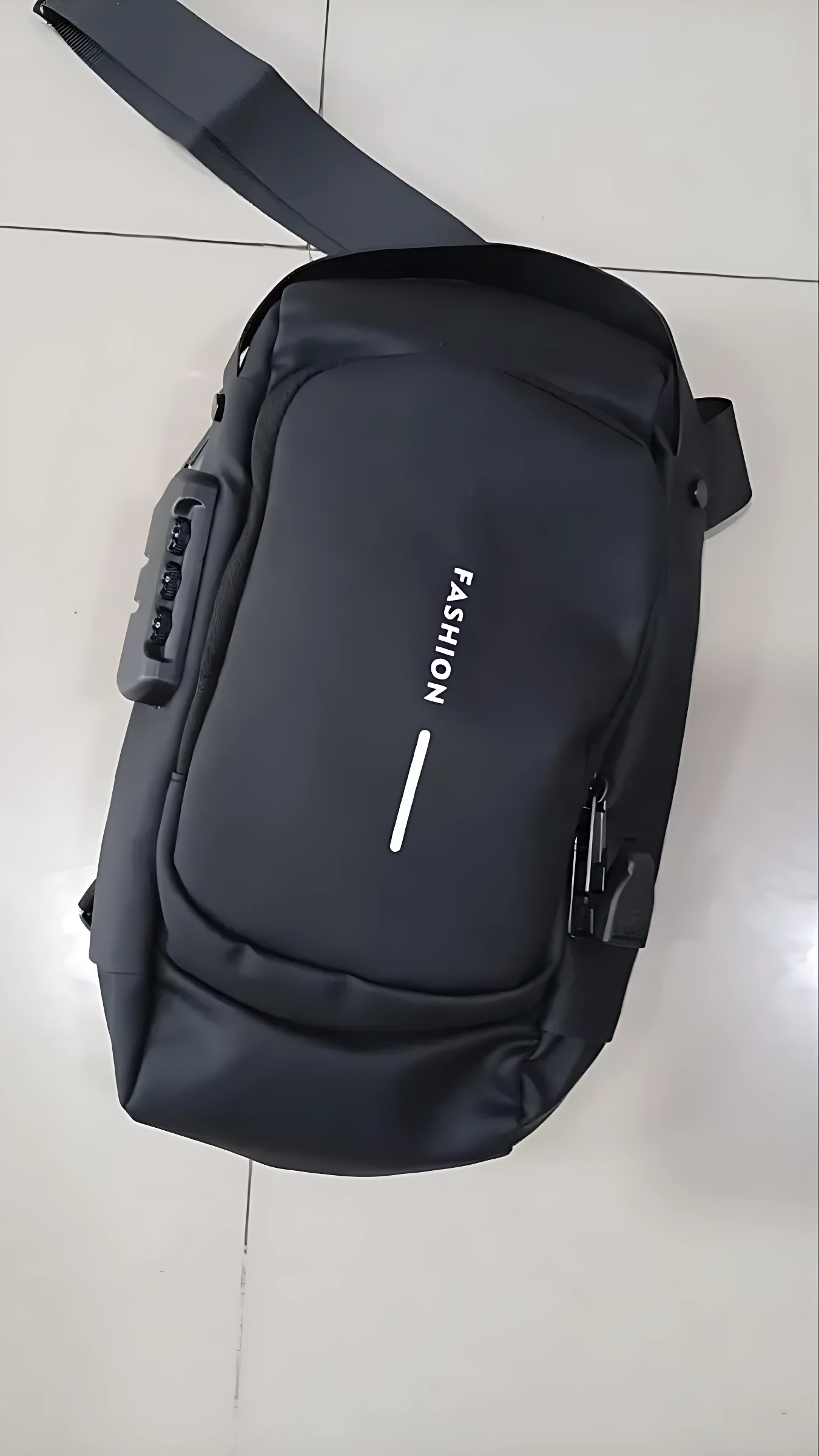 Morral rígido antirrobo negro con combinación, vista superior mostrando asa lateral y logo "FASHION" en frontal.