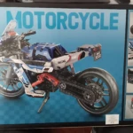 Caja de kit de construcción de motocicleta deportiva en colores azul, blanco y rojo, con detalles en negro y rojo, mostrando el modelo ensamblado y vistas parciales del producto.