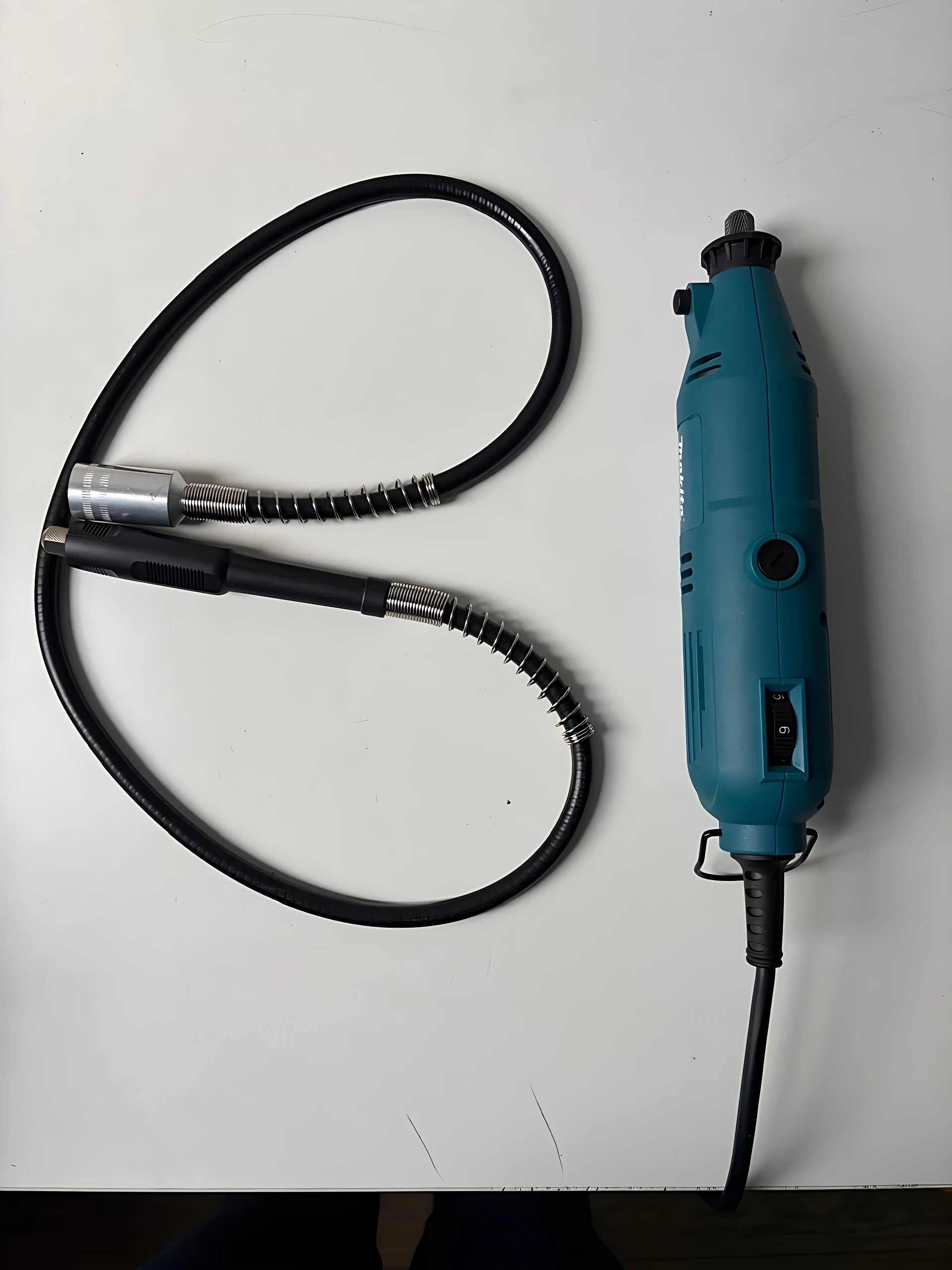 Makita motortool de alta velocidad en color azul, con cable negro enrollado y accesorios metálicos visibles sobre fondo blanco.