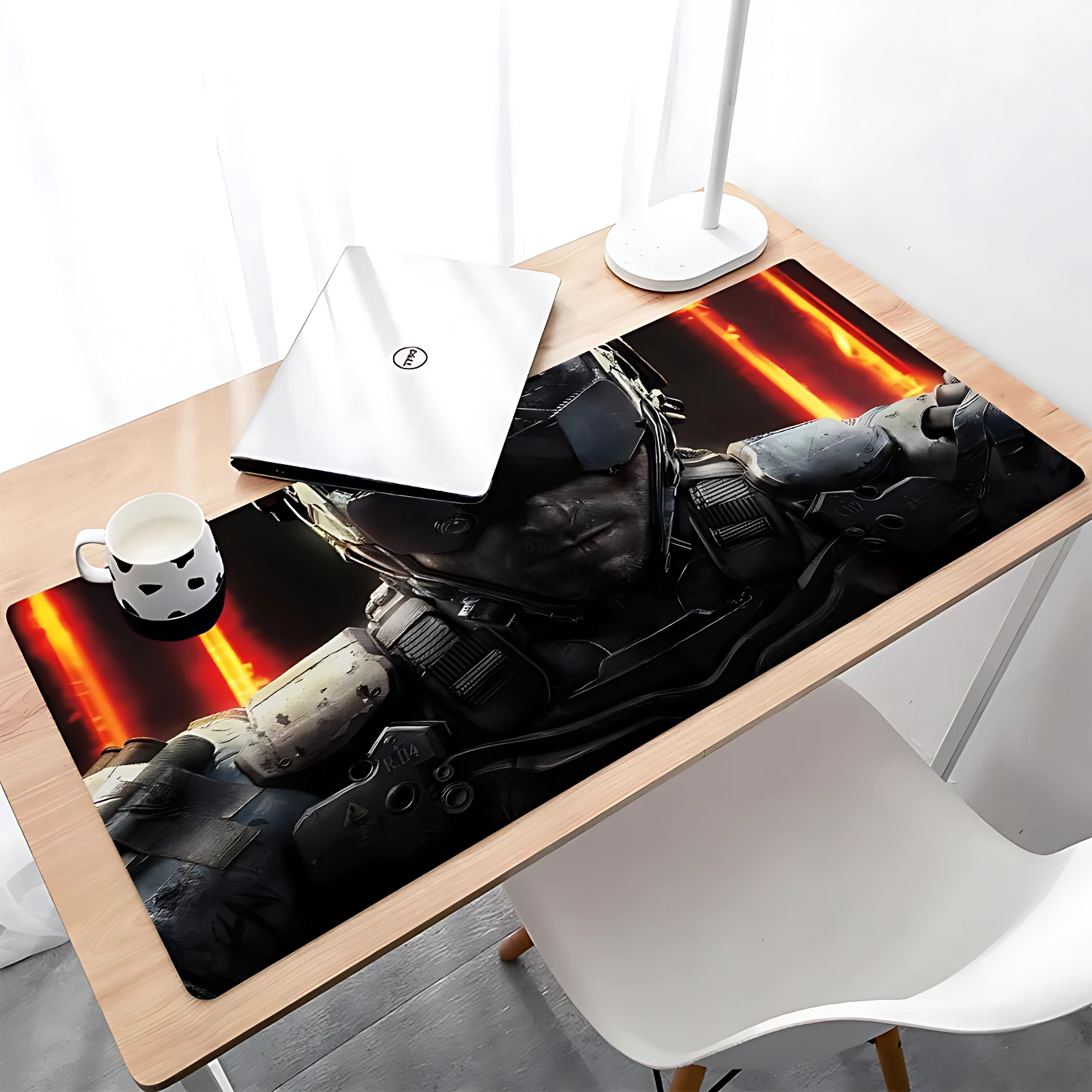 Mousepad gamer XL con diseño de soldado futurista sobre fondo rojo y negro, colocado en escritorio junto a laptop y taza.