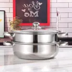 Olla vaporera de acero inoxidable con tapa de vidrio y dos niveles, sobre encimera blanca en cocina decorada.
