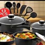 Set de cocina negro con ollas y sartenes, incluye utensilios de cocina y platos con comida preparada.