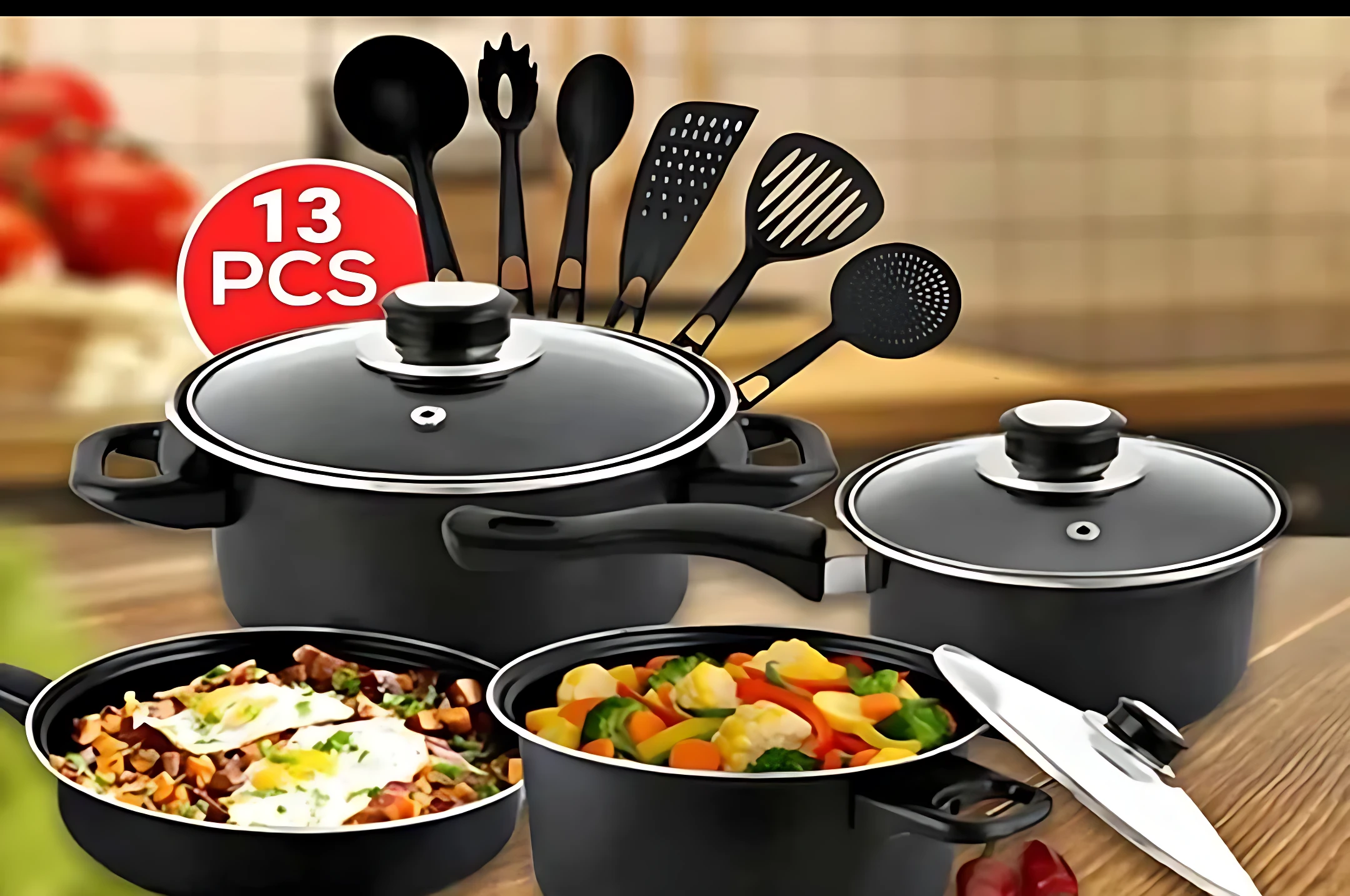 Set de cocina negro con ollas y sartenes, incluye utensilios de cocina y platos con comida preparada.