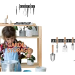 Organizador de pared negro con ganchos metálicos, mostrando herramientas de jardinería colgadas: rastrillo, pala, horquilla y regadera. Incluye estante de madera con macetas y niño plantando.