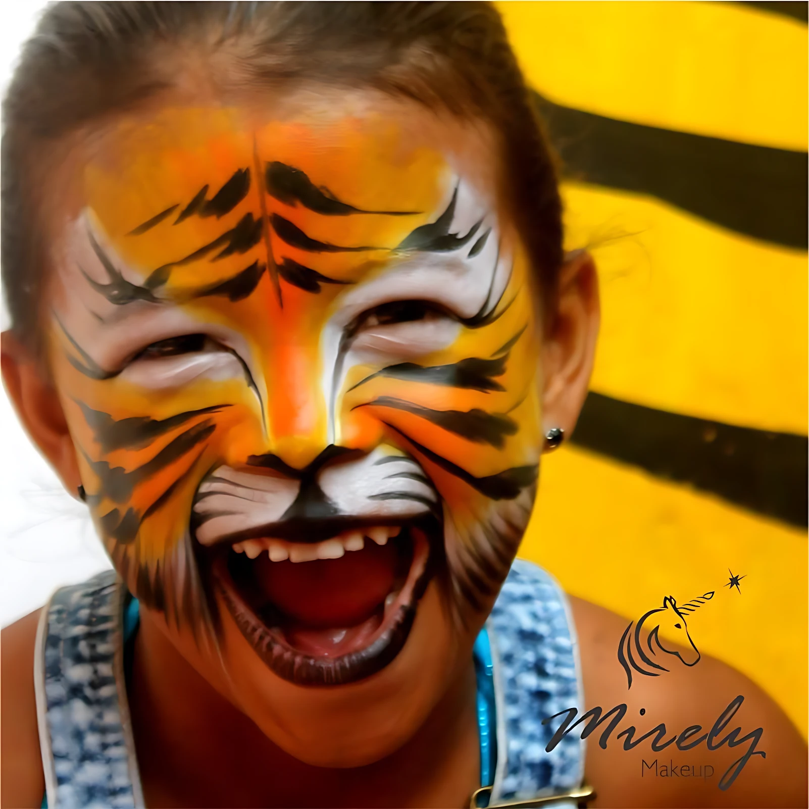 Niña sonriente con maquillaje facial de tigre en tonos naranjas, negros y blancos, mostrando diseño detallado con bigotes y dientes; fondo amarillo con rayas negras.