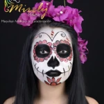 Modelo con maquillaje artístico estilo calavera de Día de Muertos, diseño facial detallado en blanco, negro y rosa, con flores magenta en la cabeza.