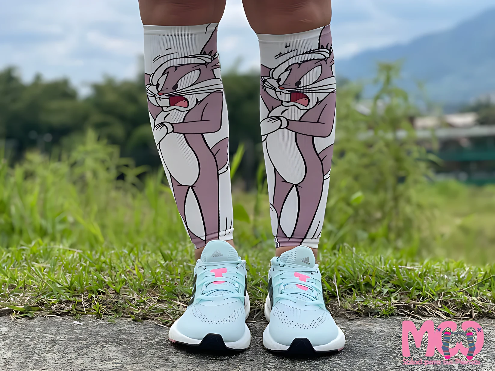 Pantorrilleras de compresión con diseño de Bugs Bunny en tonos rosados y blancos, usadas con zapatillas deportivas azules sobre césped.
