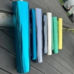 Set de dos rollos de papel polarizado para ventanas en colores azul, gris, blanco, verde y amarillo, dispuestos sobre superficie de madera.
