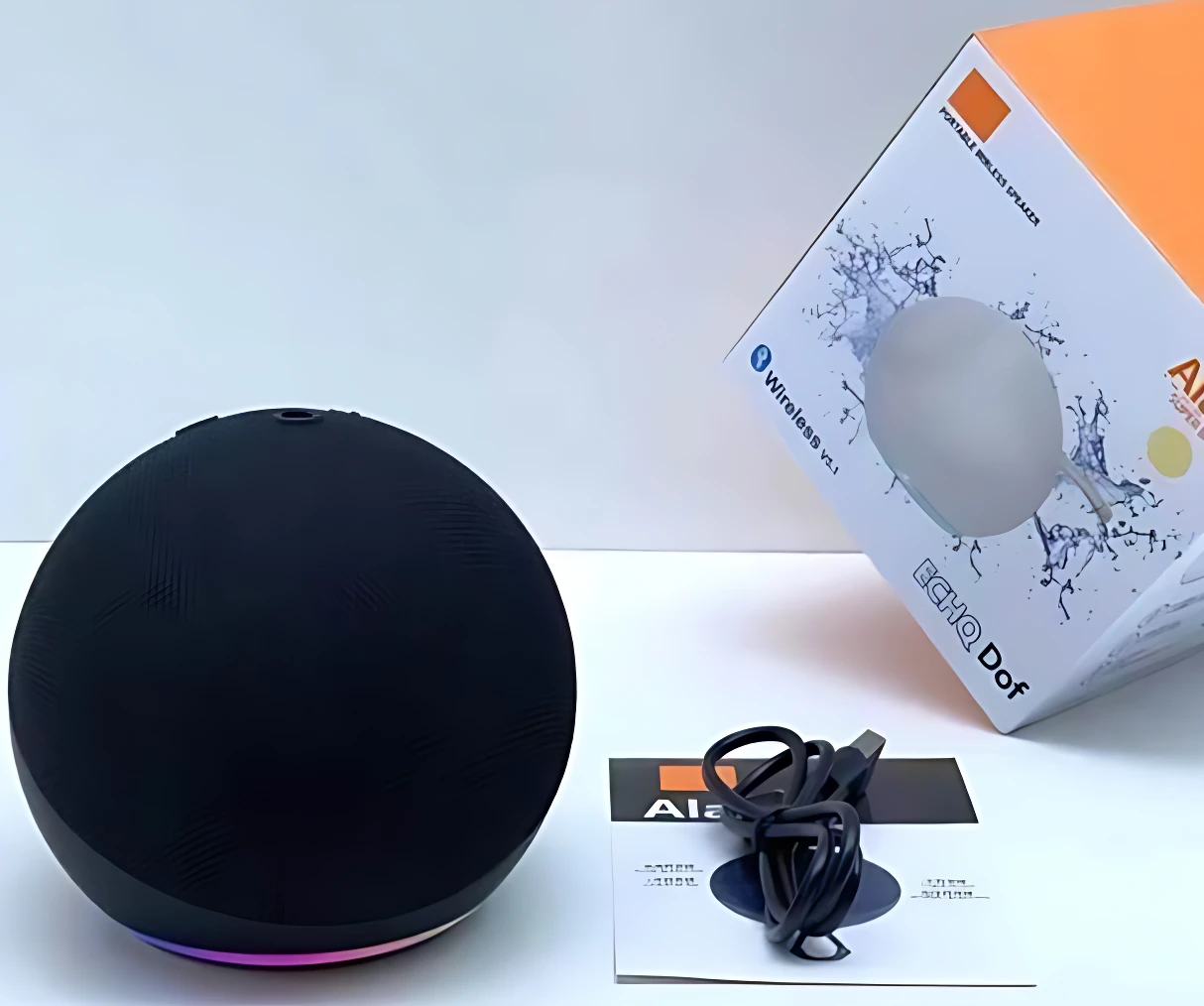 Parlante Alaxe inalámbrico negro esférico con base de luces multicolor, acompañado de su caja, cable USB y manual en superficie blanca.
