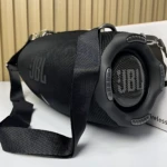 Altavoz JBL Xtreme 4 negro con correa de transporte, mostrando rejilla frontal y logotipo lateral sobre caja blanca.
