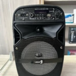 Parlante Lz 805 negro con panel de control frontal, rejilla circular y logo visible. Incluye micrófono integrado y luces LED.