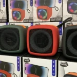 Cuatro parlantes Bluetooth X-911 en colores azul, verde, rojo y negro, exhibidos sobre cajas de su empaque original.