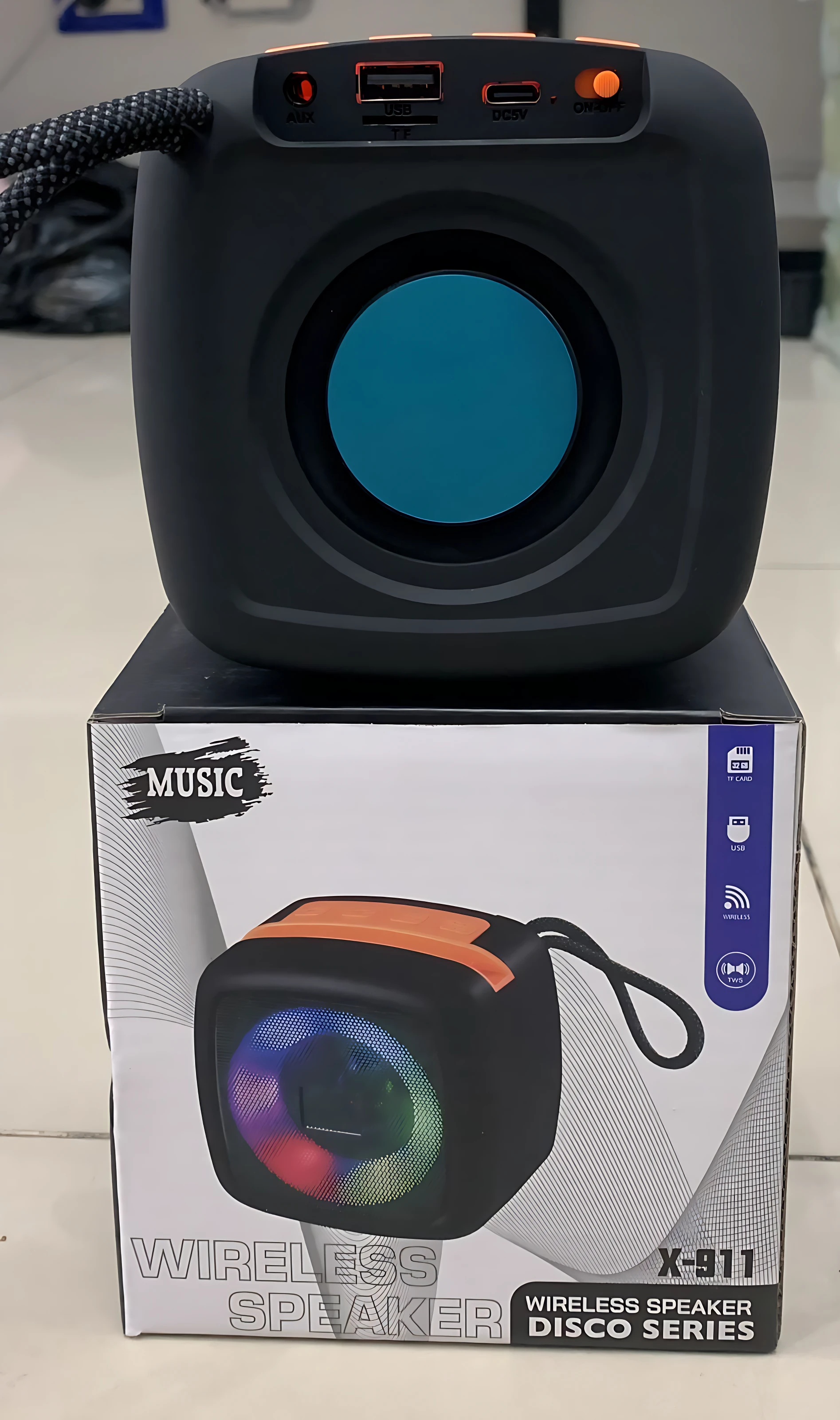 Parlante inalámbrico negro con detalles naranjas, modelo X-911, sobre su caja de venta al por menor.