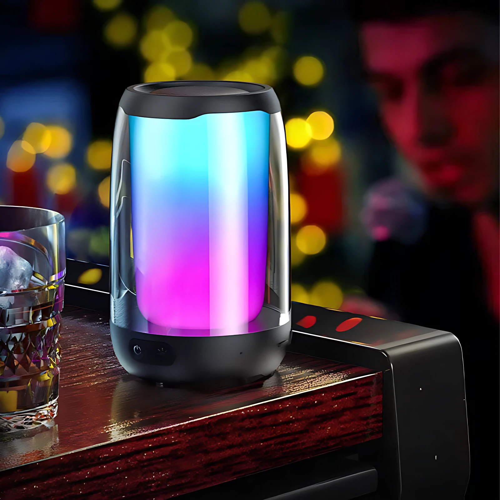 Parlante Remax Bluetooth con luces LED multicolor en ambiente nocturno, sobre superficie de madera junto a vaso de bebida.