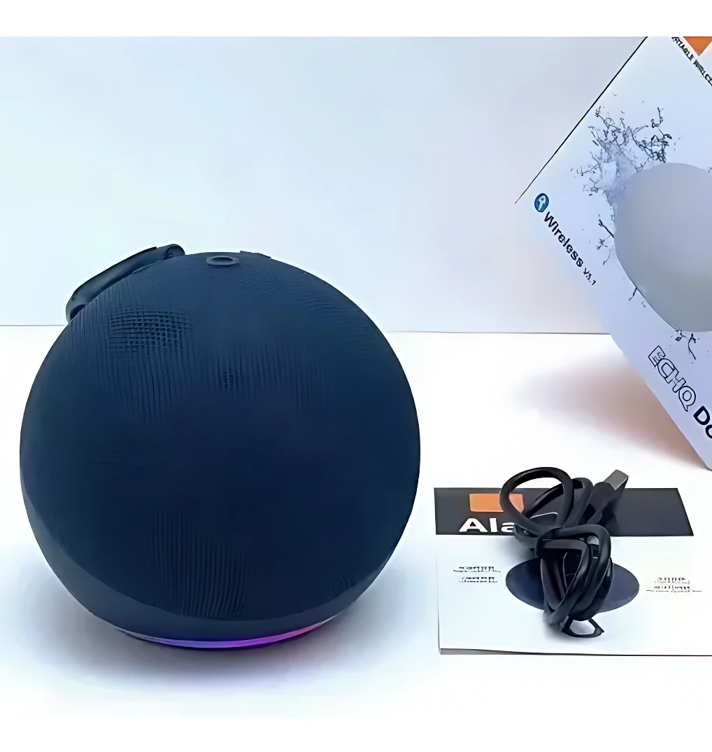 Parlante inteligente esférico negro con luz LED púrpura en base, cable USB y caja visible al fondo.