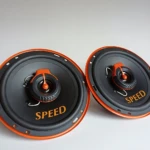 Dos parlantes automotrices de 6.5 pulgadas, color negro con detalles en naranja, marca SPEED, montados sobre fondo blanco.