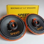 Parlantes automotrices Speed de 6.5 pulgadas, color negro con detalles naranjas, mostrando dos unidades frente a su caja amarilla con texto visible.
