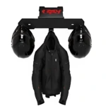 Soporte de pared negro con logo rojo, mostrando dos cascos integrales colgados a los lados y una chaqueta de cuero en el centro.