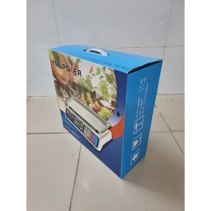 Caja azul de báscula electrónica de mesa con teclado numérico, mostrando del producto en uso sobre frutas y verduras.
