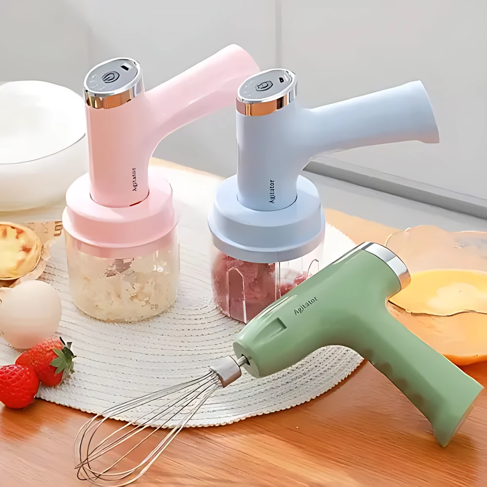 Tres picadoras eléctricas de 250 ml en colores rosa, azul y verde, con accesorios visibles: batidor y contenedores llenos de ingredientes frescos sobre superficie de madera.