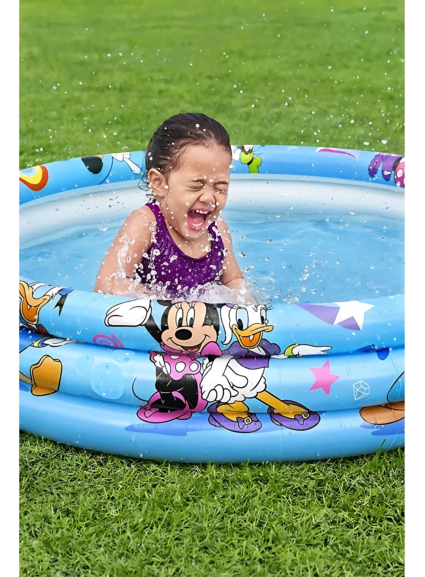 Niña riendo en piscina inflable azul con Mickey Mouse, Donald y Minnie, sobre césped verde.
