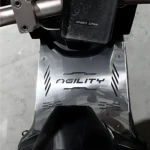 Vista superior del piso Agility de acero inoxidable para scooter, con acabado brillante y detalles en relieve, montado en la parte inferior de una motocicleta.