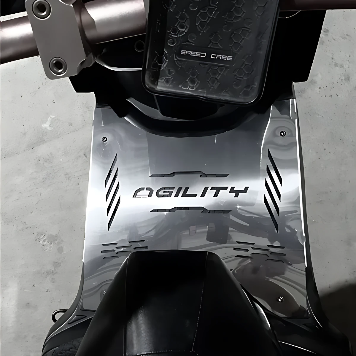 Vista superior del piso Agility de acero inoxidable para scooter, con acabado brillante y detalles en relieve, montado en la parte inferior de una motocicleta.