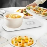 Plato eléctrico calentador blanco con aislamiento térmico, manteniendo calientes platos de comida y una taza de sopa en mesa de comedor.