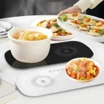 Plato eléctrico calentador blanco y negro con aislamiento térmico, mostrando dos variantes de color sobre mesa con platos de comida caliente.