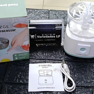 Procesador de alimentos inalámbrico blanco con caja, manual y cable de carga sobre superficie oscura texturizada.