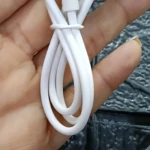 Cable de carga blanco enrollado en mano, con conector USB tipo A y micro USB, sobre fondo texturizado oscuro.