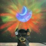 Proyector de noche en forma de astronauta gris, con luces multicolores y estrellas proyectadas en la pared. Incluye parlante integrado y diseño amigable para niños.