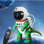 Proyector Galaxy Dinosaurio Astronauta verde con detalles naranjas y amarillos, control remoto negro visible, fondo espacial con planeta azul.