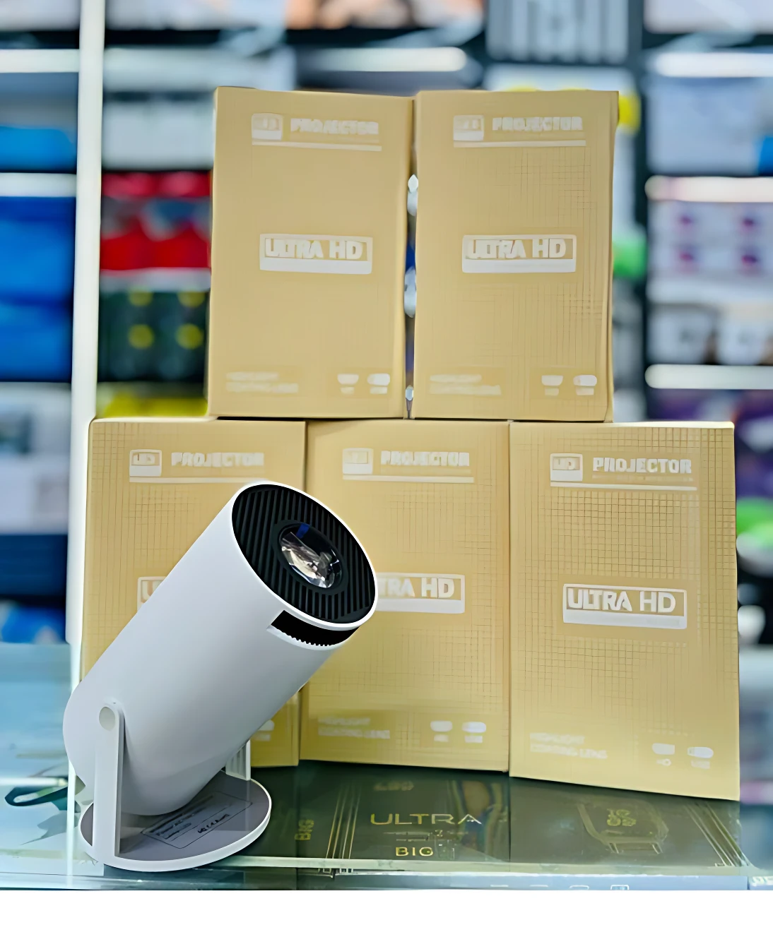 Proyector blanco con lente negra, sobre caja amarilla que dice Ultra HD, en mostrador de tienda.