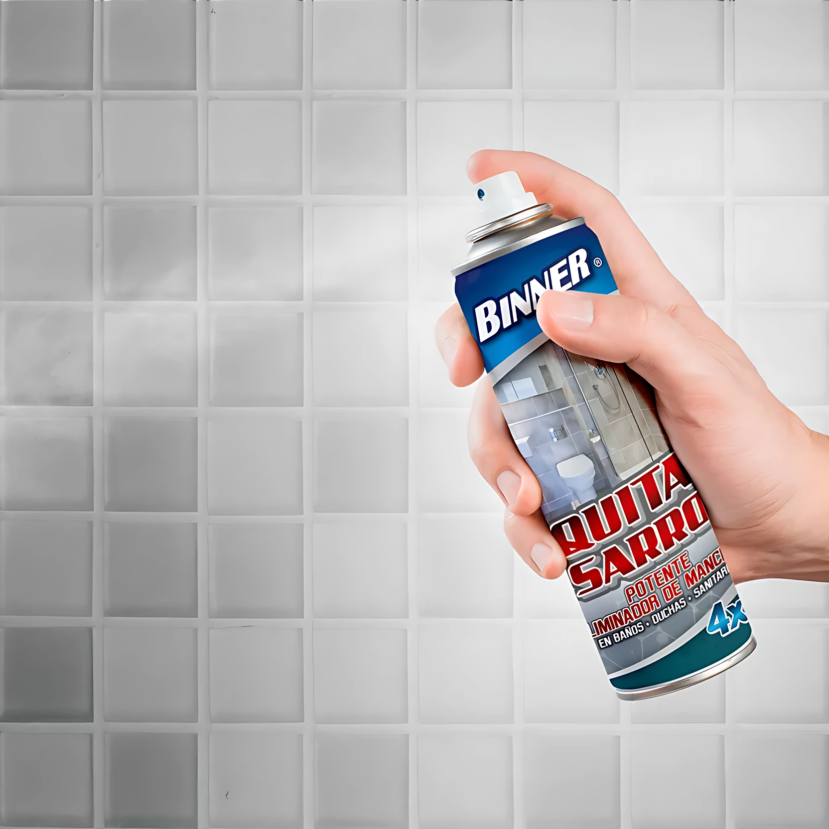 Mano sosteniendo aerosol Binner Quita Sarro 400ml, aplicando espuma blanca sobre baldosas grises en baño. Etiqueta azul y roja visible.