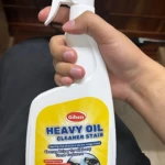 Botella de quitagrasa Heavy Oil de Gihen, con etiqueta amarilla y blanca, en mano sobre fondo oscuro.