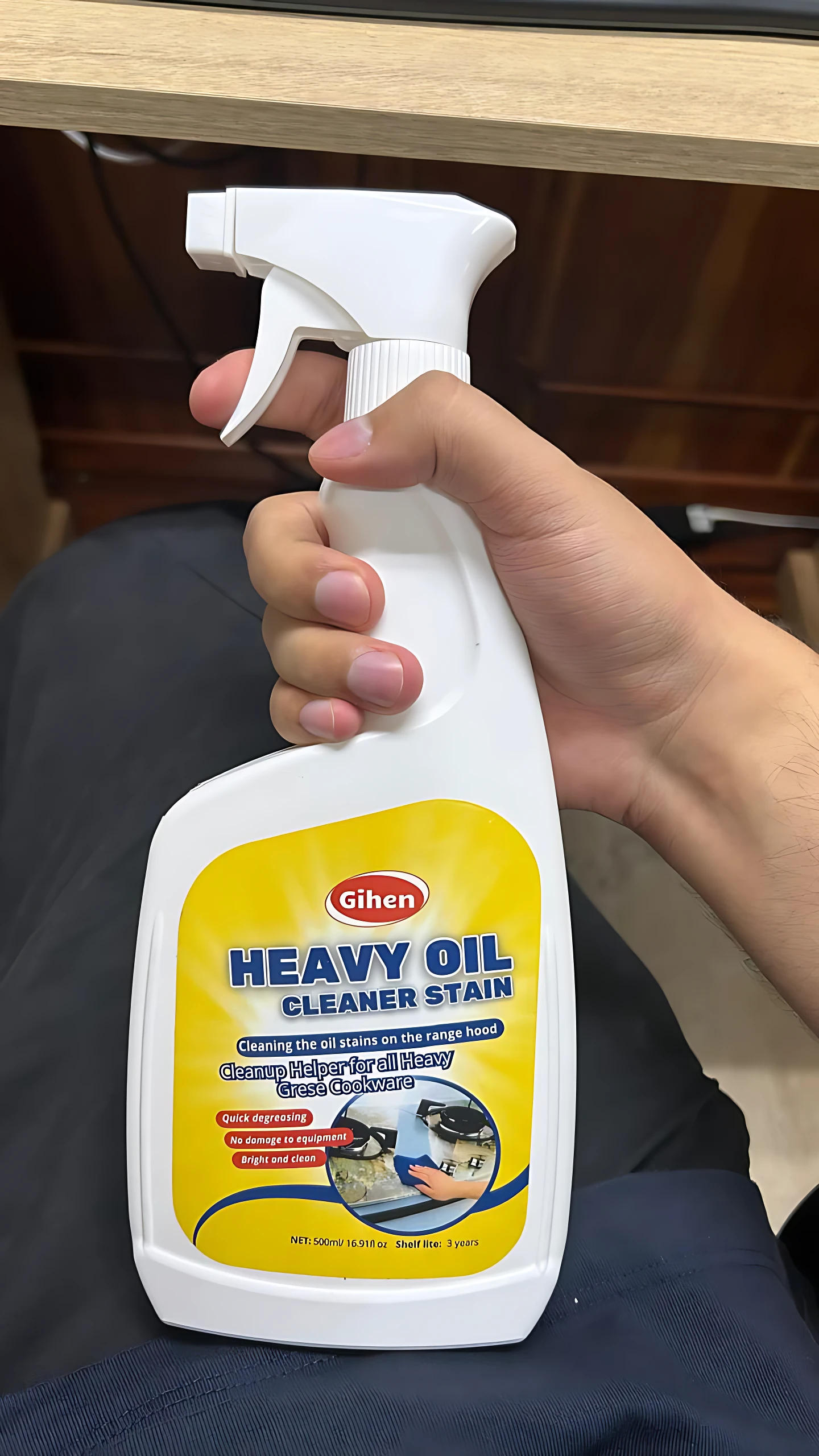 Botella de quitagrasa Heavy Oil de Gihen, con etiqueta amarilla y blanca, en mano sobre fondo oscuro.