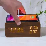 Reloj despertador de madera con carga inalámbrica para smartphone, mostrando hora, temperatura y humedad en pantalla LED.
