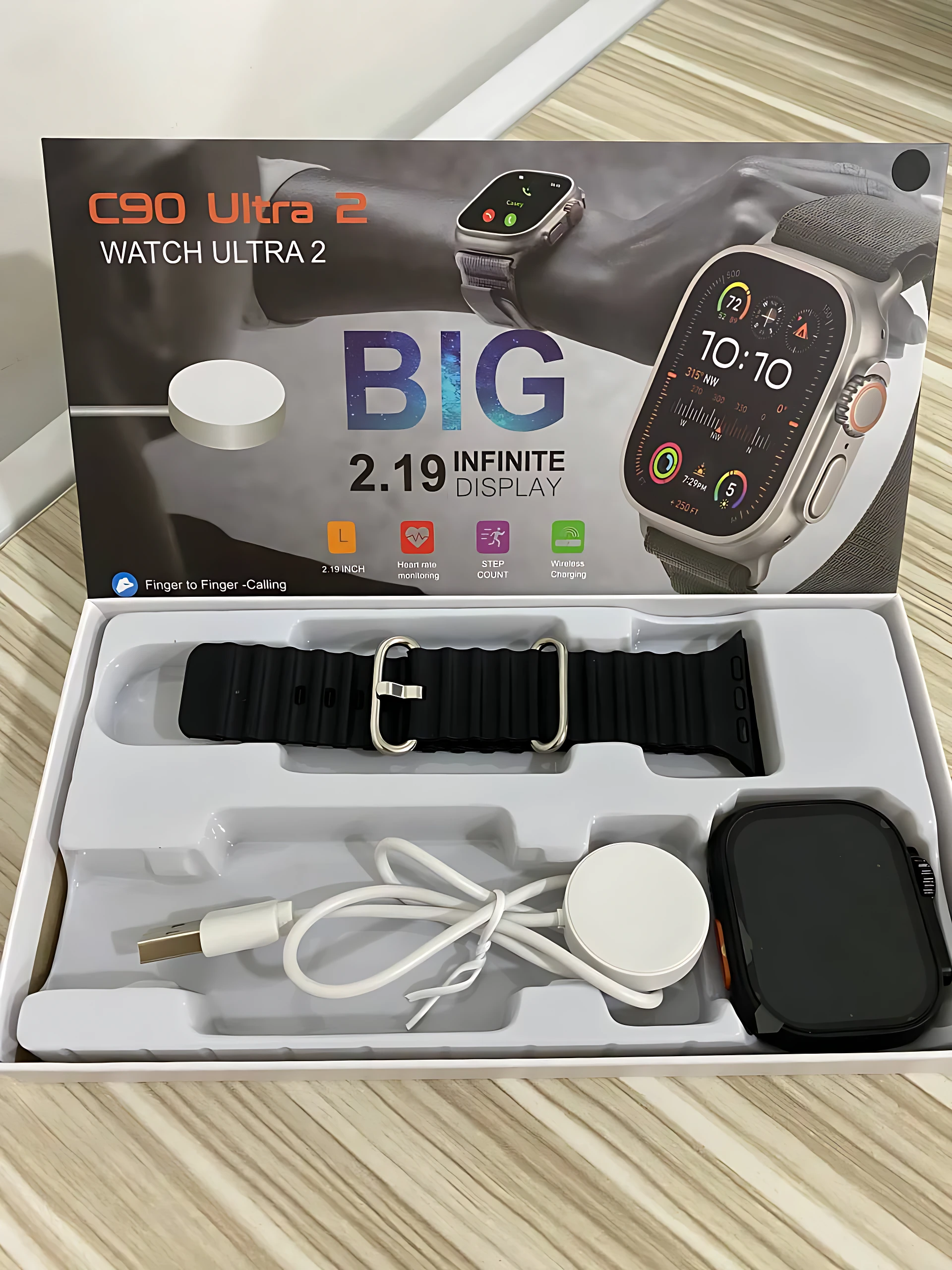 Smartwatch C90 Ultra 2 en caja abierta: pulsera negra, cargador, cable USB y caja protectora. Pantalla de 2.19 pulgadas visible en la caja.
